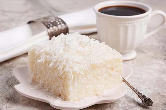 A Desiccated Coconut bar near a cup of tea and a spoon